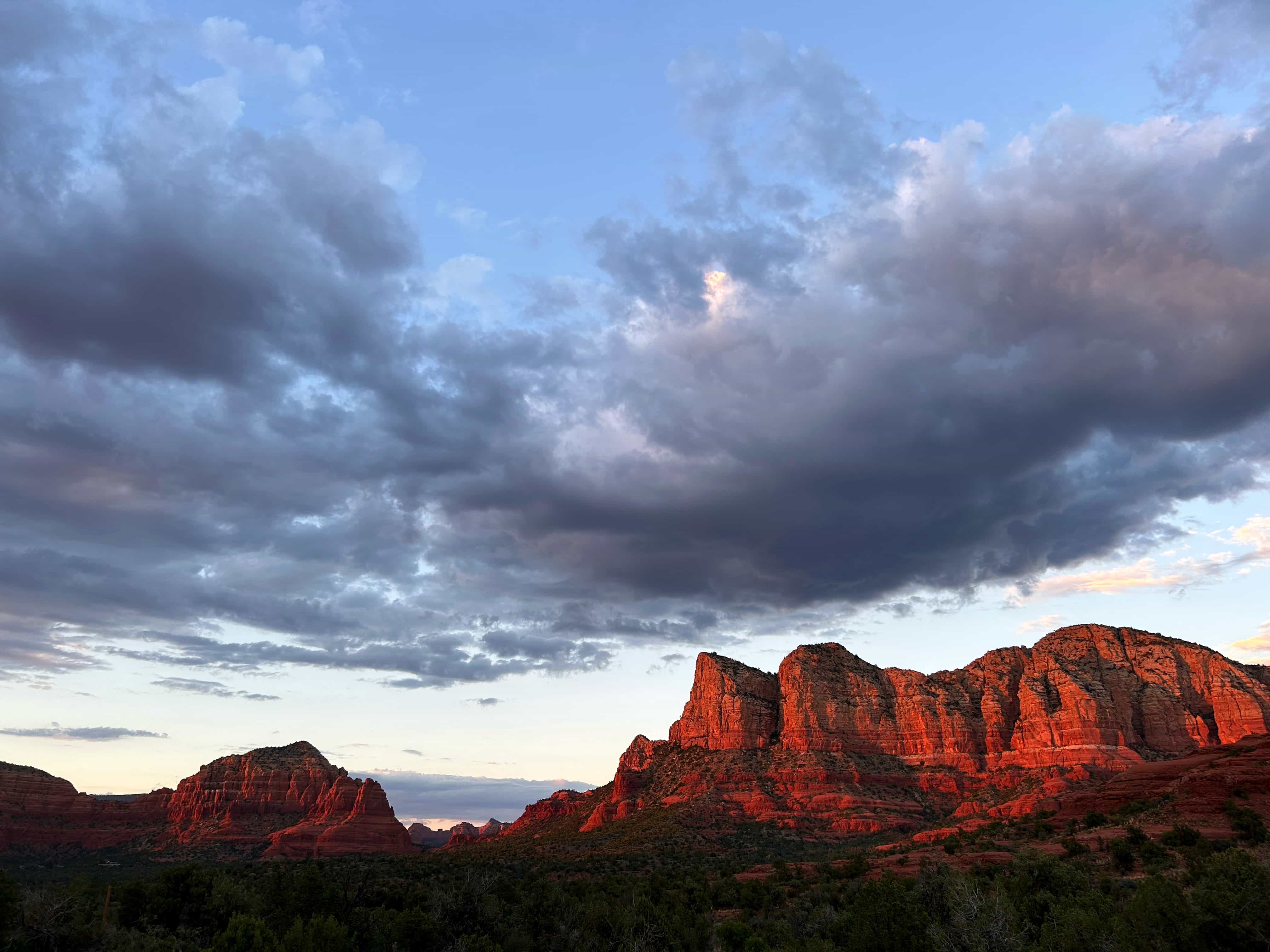 Red rock formations glowing at sunset under dramatic clouds in Sedona, Arizona
